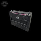 A black guitar amplifier head photographed at an angle against a solid black background, with a pinkish-purple illuminated control strip along the top edge. A Tone Shop watermark is visible in the upper left corner.