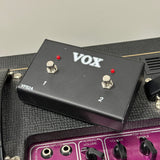 A black Vox VFS2A guitar effects pedal with silver footswitches and red indicator lights, resting on a purple and black amplifier head.