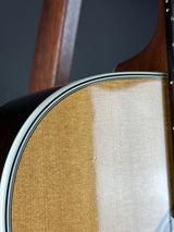 Close-up detail of an acoustic guitar body showing the natural wood soundboard, black back, white binding, and part of the wooden neck.
