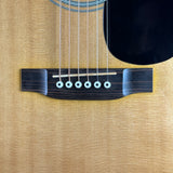 Close-up of an acoustic guitar's bridge and six strings against a natural wood body.