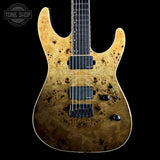 A double-cutaway electric guitar with a natural figured burl wood top, showing prominent dark grain patterns. It features black hardware, including a black bridge, pickups, and control knobs, and is photographed against a solid black background with a Tone Shop watermark in the upper left corner.