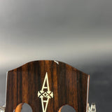 Close-up of the headstock of a guitar, showing a dark brown wood grain finish, a cream-colored inlaid 'A' logo, and the tuning peg holes, set against a dark gray background.