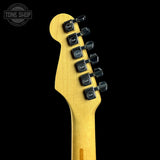 Close-up of the headstock of a Fender electric guitar in a natural maple finish, showing six black tuning pegs with Fender logos, set against a solid black background.