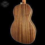 Close-up of the back of a wooden ukulele or small guitar showing a rich brown wood grain finish with a light cream edge trim, set against a solid black background. A Tone Shop watermark is visible in the top-left corner.