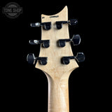 Close-up rear view of an electric guitar headstock made of light natural wood with six black tuning pegs, shown against a solid black background.