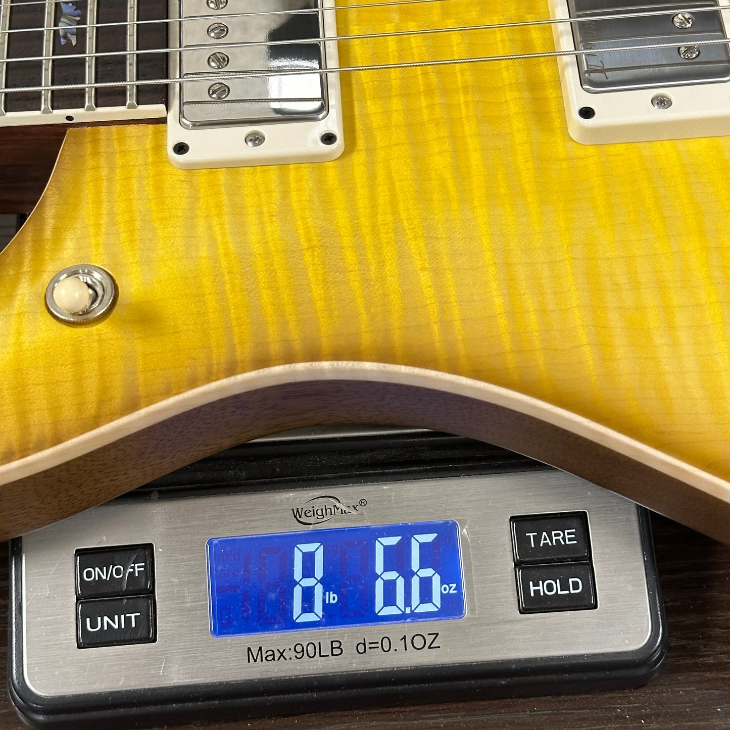 Yellow electric guitar on a digital scale displaying weight
