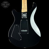 Close-up of the back of a black electric guitar body with a maple neck, showing the PRS guitars logo, pickups, and a glossy black finish against a black background.
