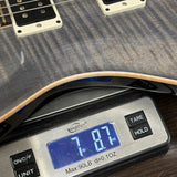 A close-up of a guitar body resting on a digital scale, showing the scale reading 7.87 lbs.