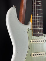 Close-up of a silver electric guitar with a dark wood neck on a black background