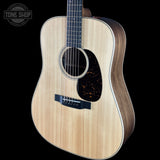 An acoustic guitar with a natural flamed maple top and dark wood sides, shown against a solid black background. A Tone Shop watermark is visible in the upper left corner.
