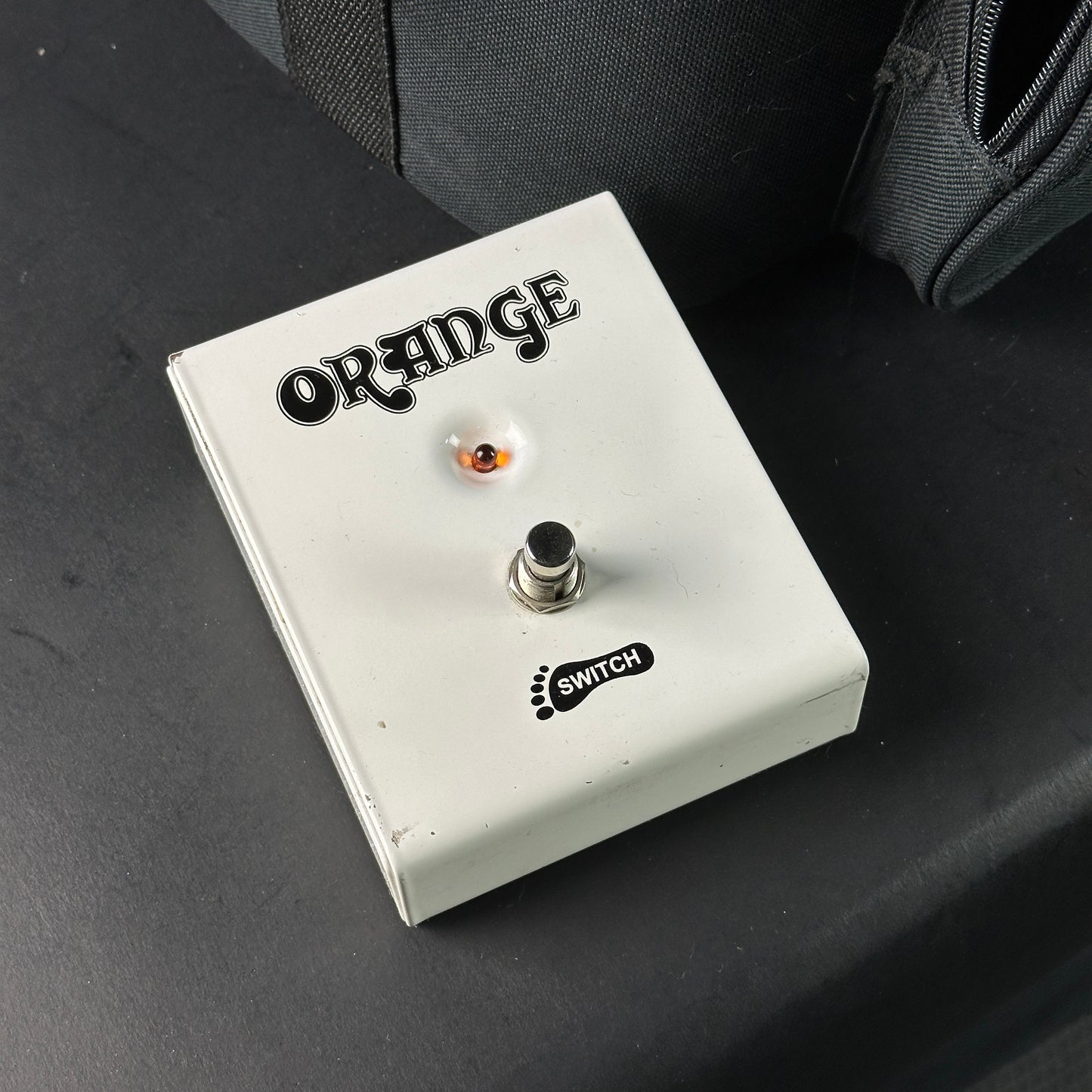 Orange guitar effects pedal on a dark surface