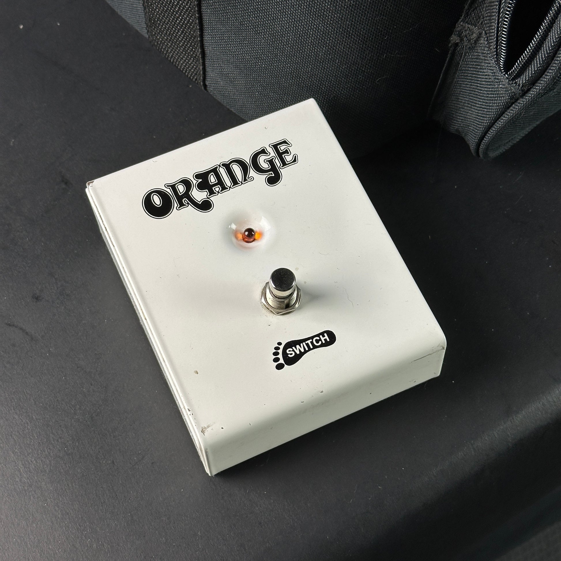 Orange guitar effects pedal on a dark surface