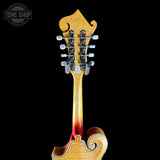 Close-up of the headstock and upper neck of a mandolin guitar against a solid black background, with a Tone Shop watermark in the top left corner.