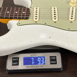 White electric guitar on a digital scale displaying weight