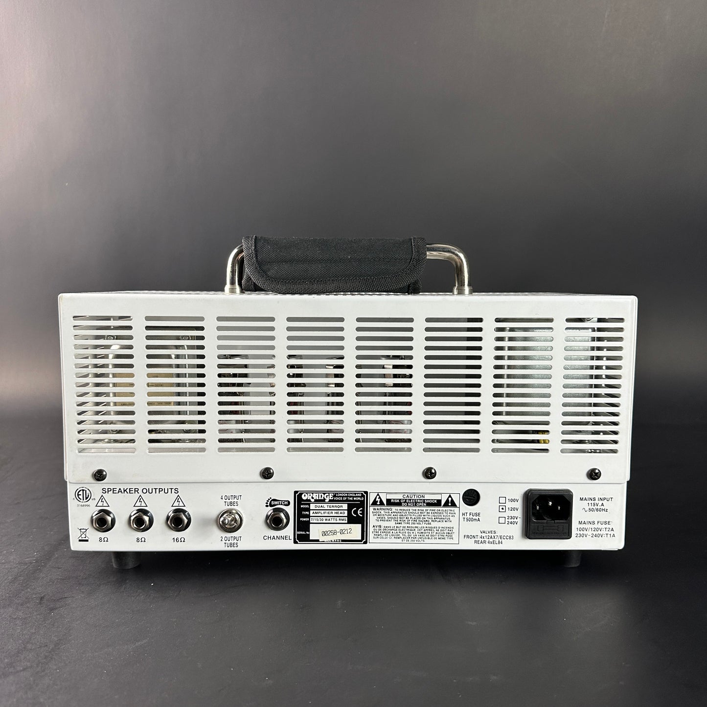 Back view of a white electronic device with control knobs and labels on a gray background