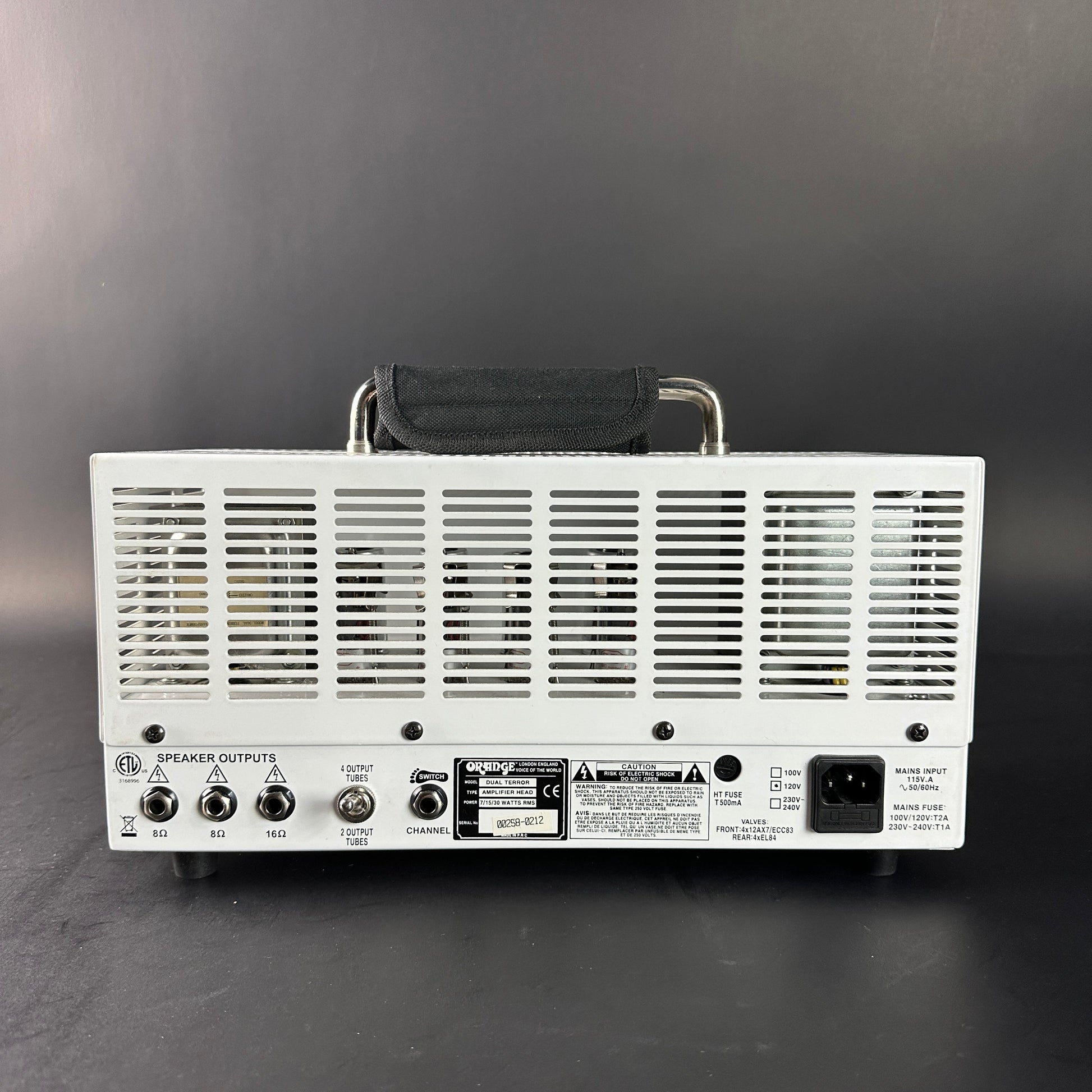 Back view of a white electronic device with control knobs and labels on a gray background