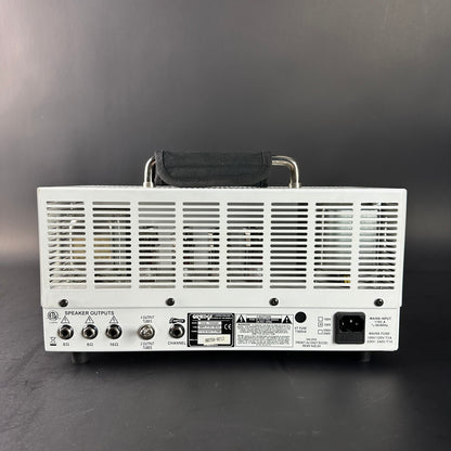 Back view of a white electronic device with control knobs and labels on a gray background