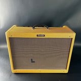 Fender guitar amplifier with yellow exterior and brown speaker grille on a gray background