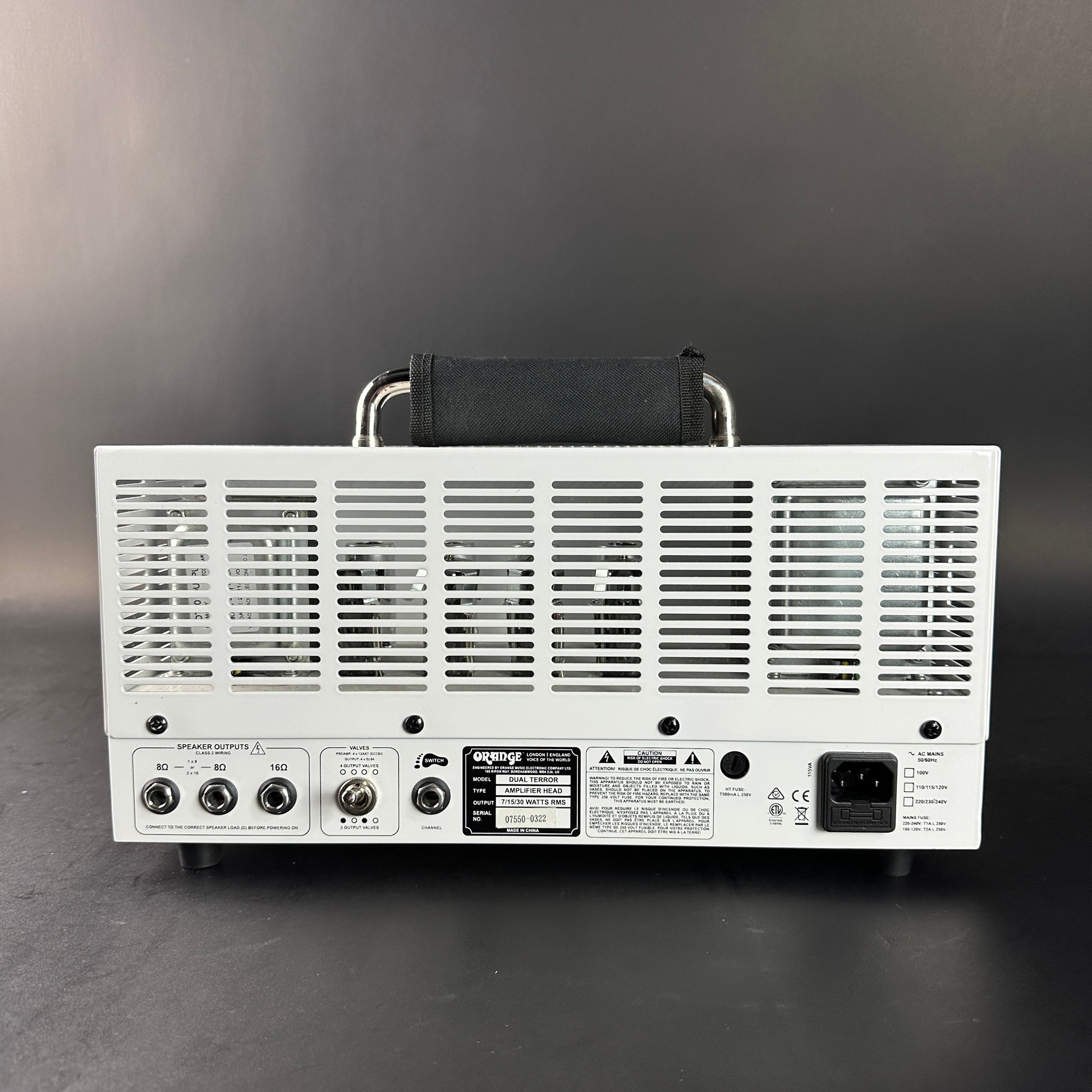 Back view of a white electronic device with control panels on a dark background