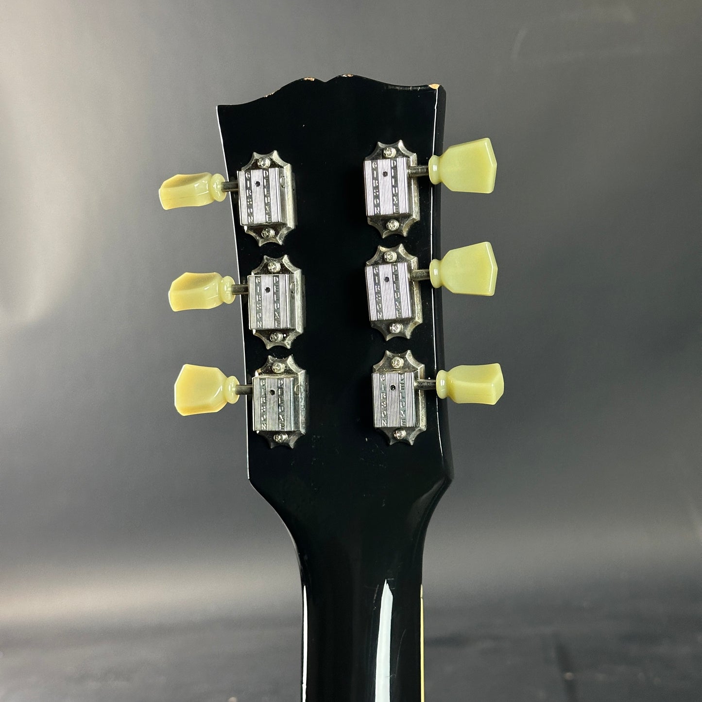 Close-up of a guitar headstock with tuning pegs on a dark background