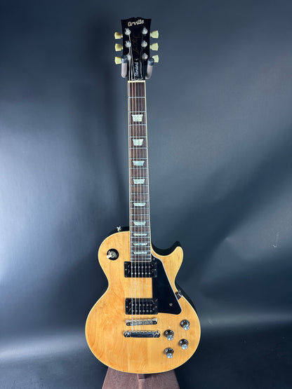 Electric guitar with a wooden body and black pickguard on a dark background
