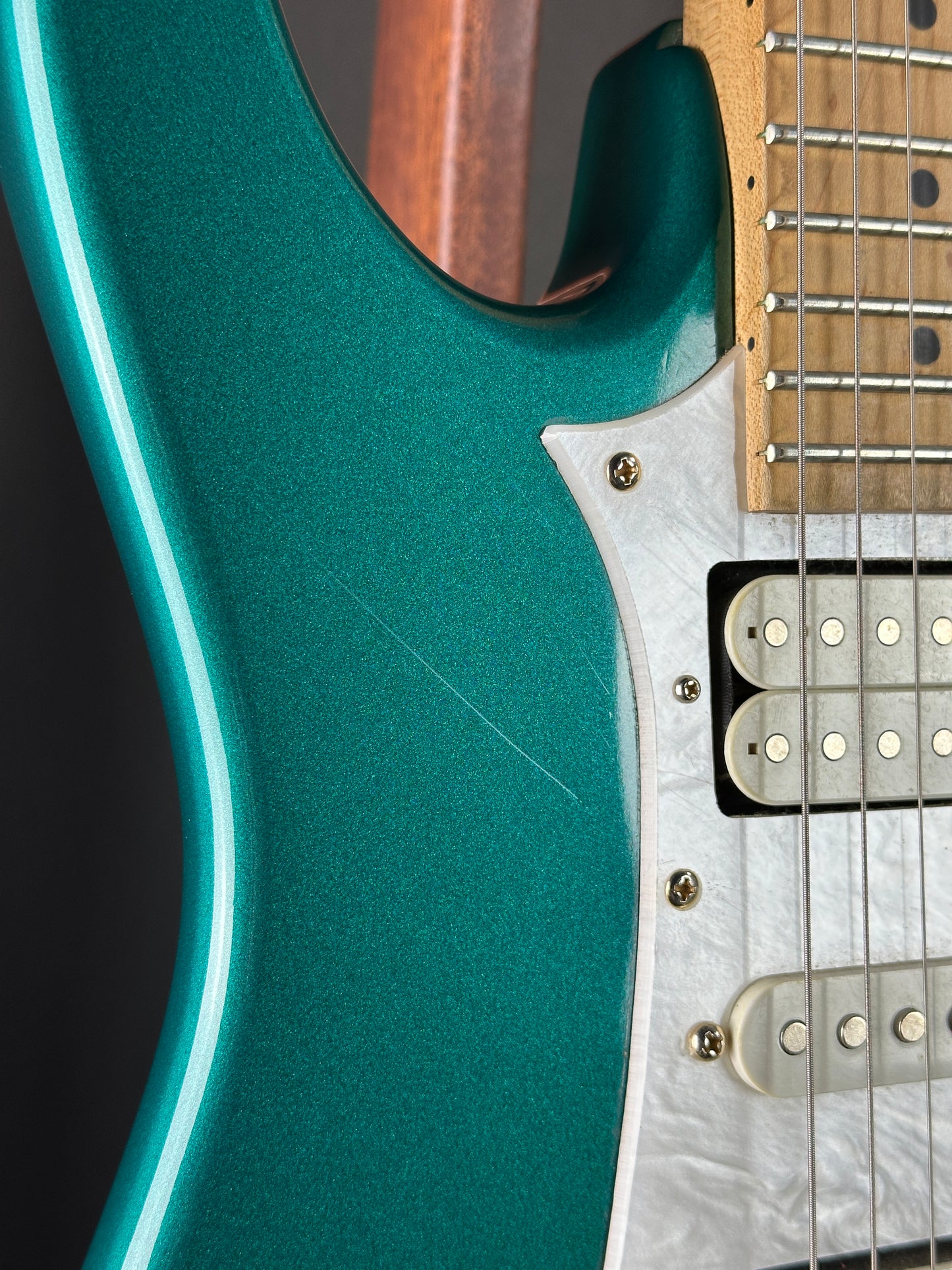 Close-up of a teal electric guitar with a focus on the body and neck.