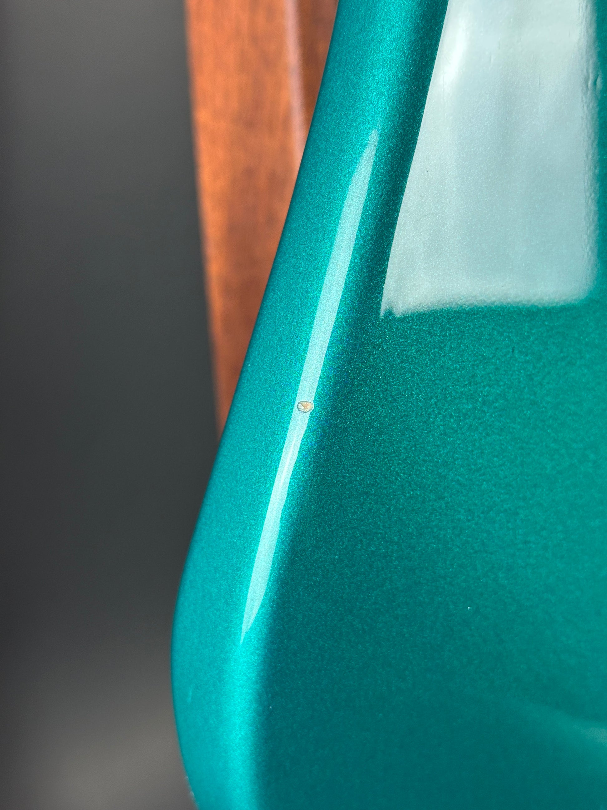 Close-up of a teal plastic object with a clear label on a dark background