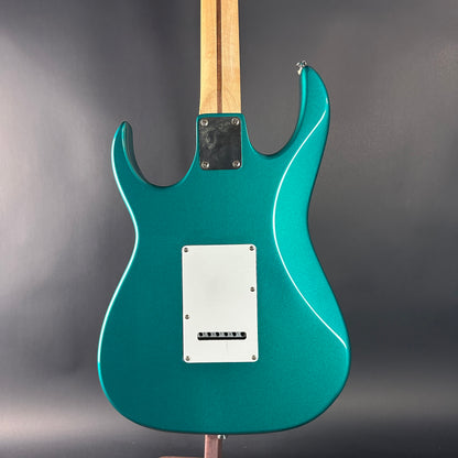 Teal electric guitar on a gray stand with a gray background