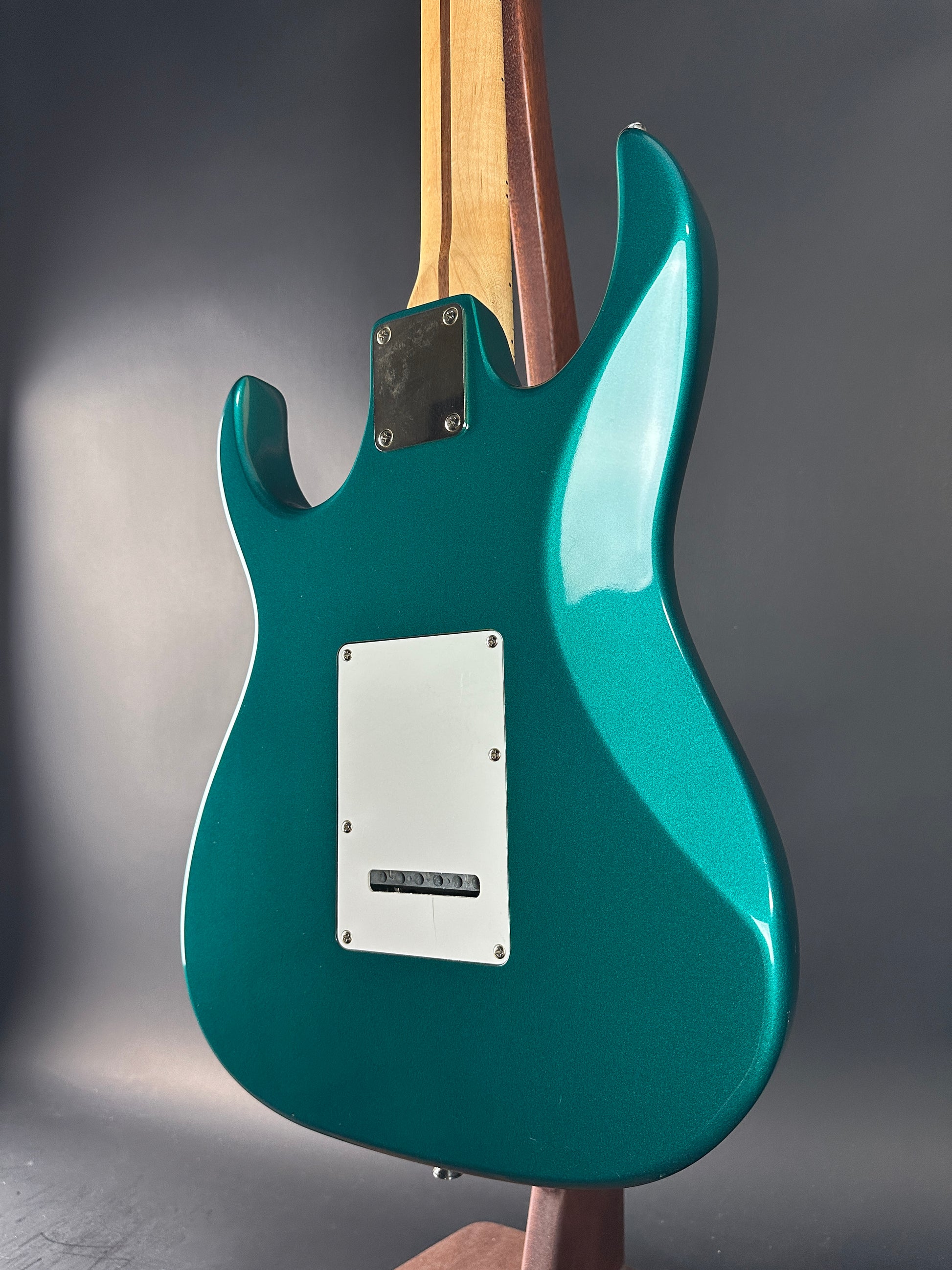 Teal electric guitar on a gray background