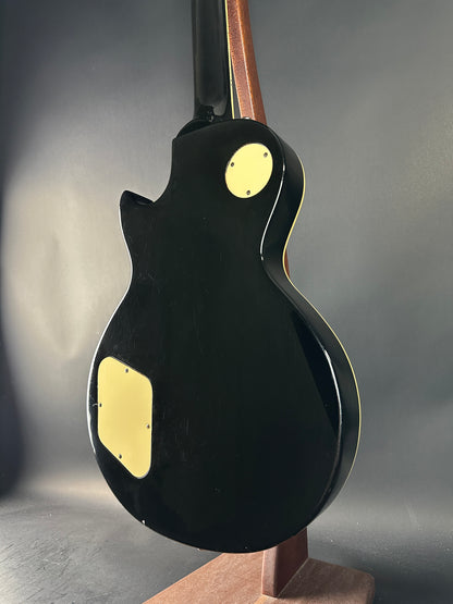 Close-up of a black electric guitar with gold hardware on a gray background