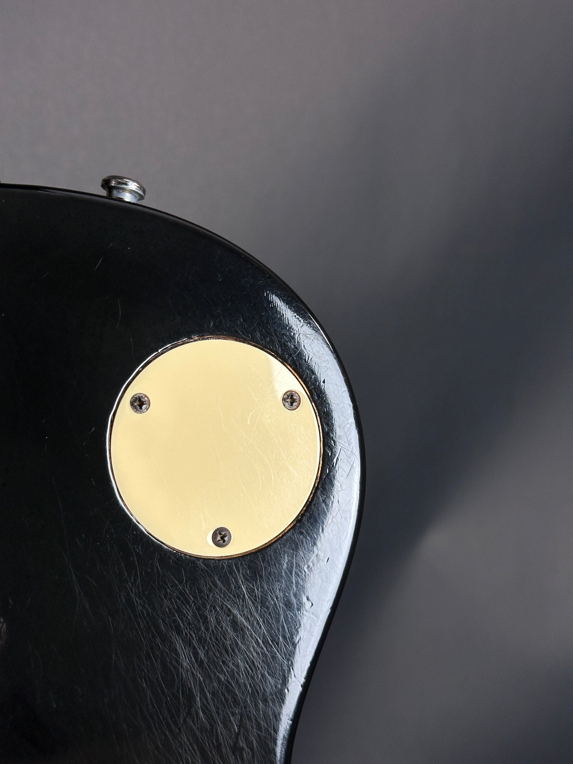 Close-up of a black object with a gold circular plate on a dark background