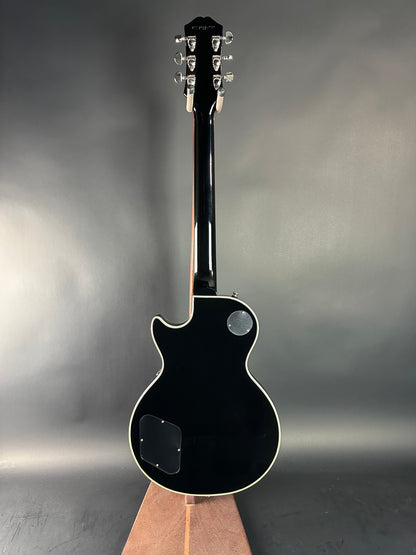 Black electric guitar on a reflective surface with a gray background