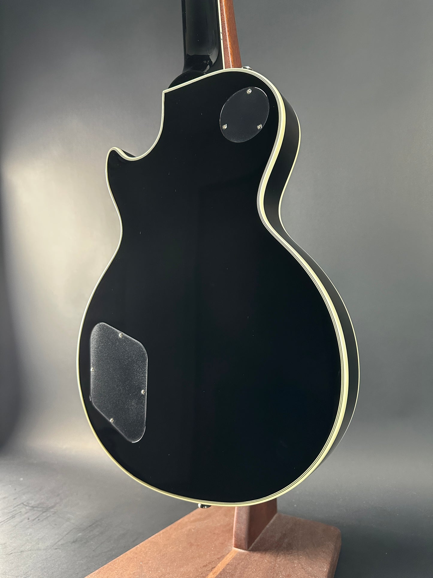 Black electric guitar body on a gray surface