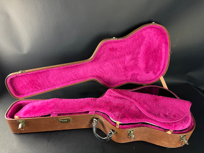 Open guitar case with pink interior on a black background