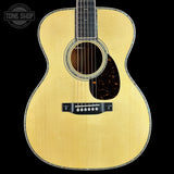 A close-up studio shot of an acoustic guitar body against a solid black background, featuring a natural wood finish, a dark tortoiseshell pickguard, and a black bridge. A 'Tone Shop' watermark is visible in the top-left corner.