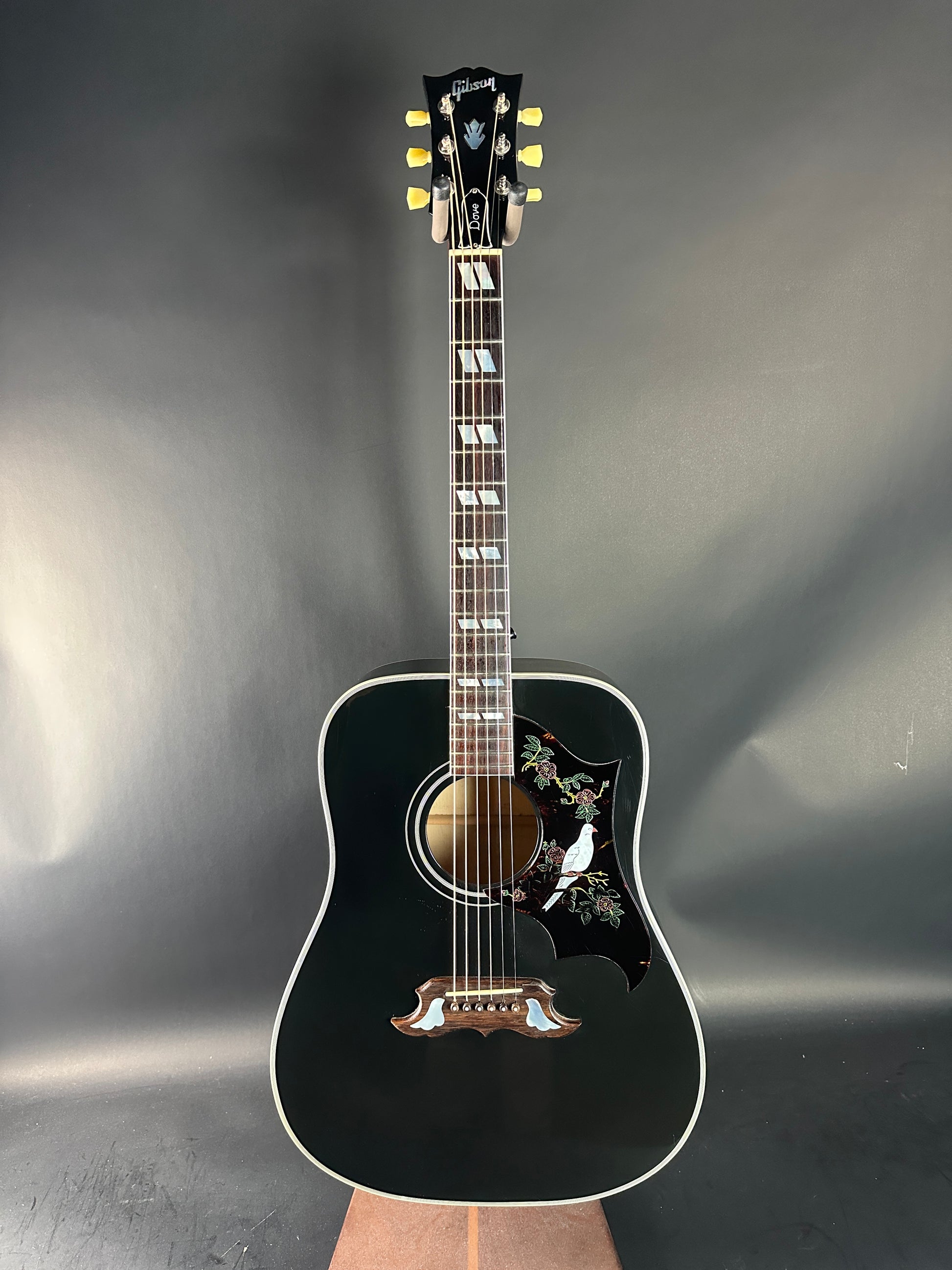 Black acoustic guitar on a reflective gray surface