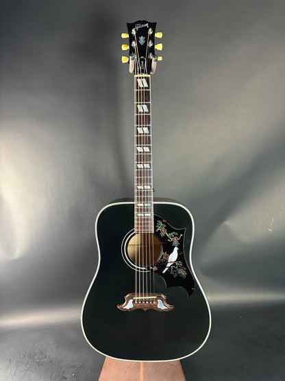 Black acoustic guitar on a reflective gray surface