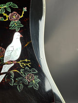 Decorative black surface with embroidered white bird and floral patterns