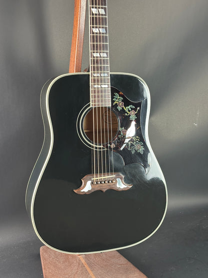 Black acoustic guitar with floral designs on a dark background