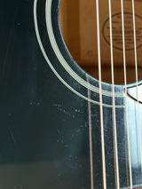 Close-up of acoustic guitar strings on a dark surface with a brand logo in the background.