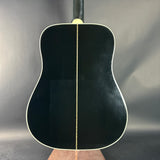 Black acoustic guitar on a stand against a gray background