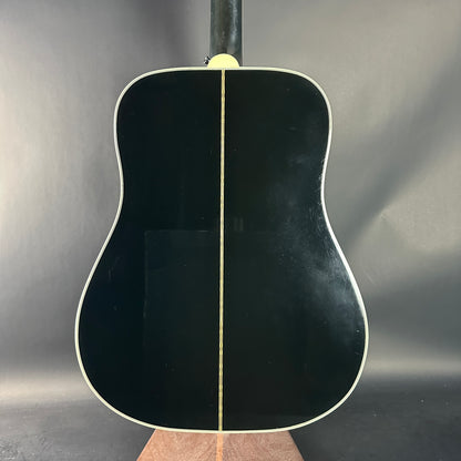 Black acoustic guitar on a stand against a gray background