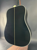 Close-up of a black acoustic guitar body on a reflective surface