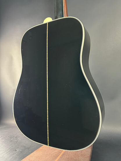 Close-up of a black acoustic guitar body on a reflective surface