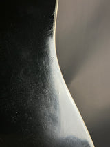 Close-up of a curved metal object with a reflective surface on a dark background