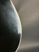 Close-up of a guitar's soundboard with visible wood grain and slight damage.