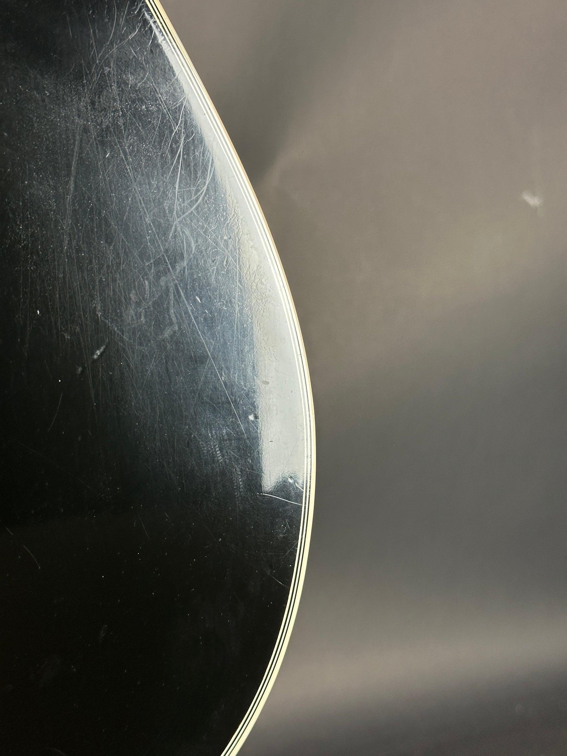 Close-up of a guitar's soundboard with visible wood grain and slight damage.
