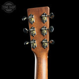 Close-up of the headstock of a guitar, showing six tuning pegs and decorative metal plates on a dark background. A Tone Shop watermark is visible in the top left corner.