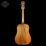 The back of an acoustic guitar with a warm honey-brown wood finish, shown against a solid black background with a Tone Shop watermark in the top-left corner.