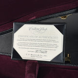 A framed Certificate of Authenticity for a Martin Custom Shop guitar, displayed inside an open dark burgundy velvet guitar case. The certificate is mounted on a black frame and features a cream-colored background with black text.